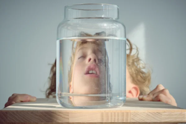 Kid playing perspective so the photo look slike his head is inside a jar