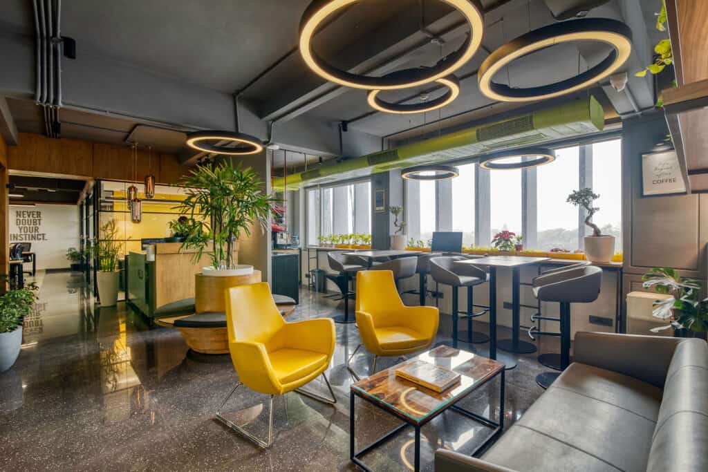 Vibrant office space with yellow chairs, hanging ring lights, and plenty of plants.
